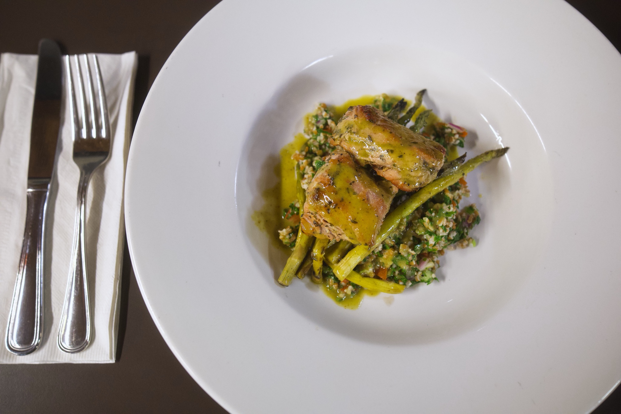 A fork and knife next to a plate of asparagus and pork tenderloin.